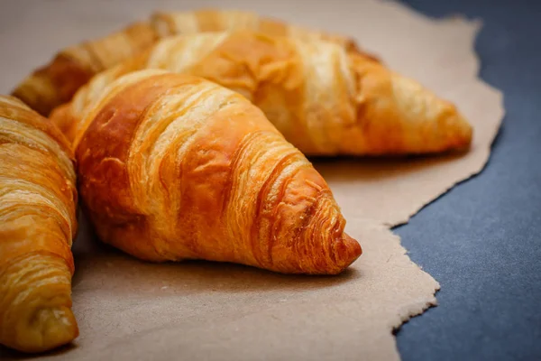 A rich variety of food photography Croissant.Four croissants on brown craft paper on a dark contrasting background.