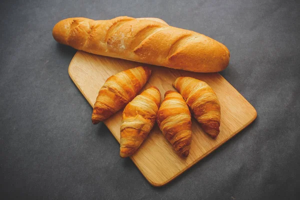 Francouzský Chléb Čtyři Croissanty Dřevěném Prkénku Temné Kraftový Papír — Stock fotografie