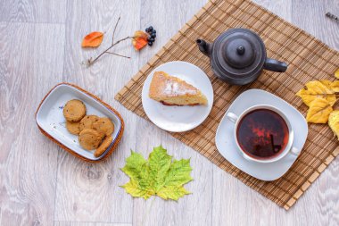 Bir fincan çay ile Erik sünger kek ve çikolata parçalı kurabiye sonbahar yaprakları çerçevede bir dilim yatak takımları bir saman üzerinde eski bir çaydanlık.