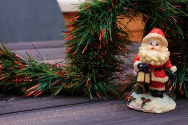 Yılbaşı dekor ve ahşap bir masa bir hediye Noel Baba ile bir kırmızı string kutusuyla şenlikli oyuncaklar