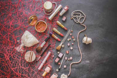 Kadın kozmetik karanlık grafit arka plan üzerinde: 3 tonları, pembe ve şeftali göz farı, benekli tozu, tuz banyoları için pembe ruj yavaşça pembe cilası, maskara, bir dizi pembe inci