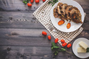 Dilimlenmiş et baharatlar, cherry domates, havuç patates yanındaki bir plaka üzerinde pişmiş tarafından çevrili bir damalı keten peçete üzerinde beyaz bir plaka üzerinde pişmiş havuç dilimleri içinde pişmiş bileşimi; Ekmek tabağı ve biber kase