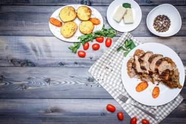 Dilimlenmiş et baharatlar, cherry domates, havuç patates yanındaki bir plaka üzerinde pişmiş tarafından çevrili bir damalı keten peçete üzerinde beyaz bir plaka üzerinde pişmiş havuç dilimleri içinde pişmiş bileşimi; Ekmek tabağı ve biber kase