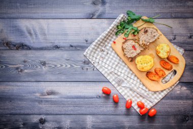 Kesme tahtası üzerinde pişmiş et iki dilim, iki dilim patates ve havuç dilimleri, keten, kareli bir peçete pişmiş bir kapta çok renkli bezelye biber ve grafit tezgahı çerçevede bir tabakta kesilmiş bir nar vardır