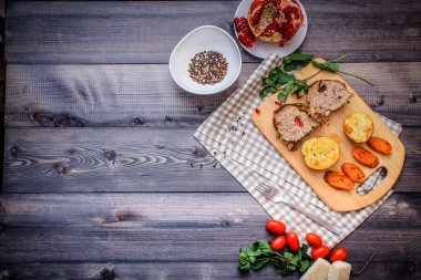 Kesme tahtası üzerinde pişmiş et iki dilim, iki dilim patates ve havuç dilimleri, keten, kareli bir peçete pişmiş bir kapta çok renkli bezelye biber ve grafit masa üstü karşı bir tabakta kesilmiş bir nar vardır