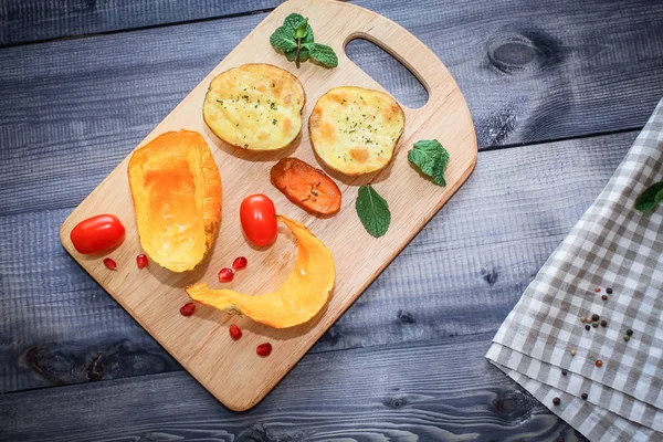 Kabak, havuç ve patates, domates ve nane hafif kesme tahtası, çatal bir koyu gri masa üstü arka plan üzerinde pişmiş dilim
