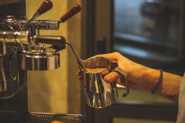 Bir adam beyaz marshmallow ile hava su bardağı kakao dökülüp sıcak içki hazırlar.