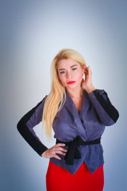 Beyaz ışık Mavi degrade arka plan için. Bir kız gri bir ceket ve kırmızı etek onun kalça sol eliyle sağ eliyle saçlarını düzeltiyor.