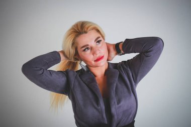 Beyaz ışık gri degrade arka plan. Gri bir ceket iki elle uzun beyaz saçlı bir kız saçını düzeltiyor.