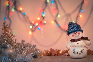 Mutlu yeni yıl tebrik kartı için arka plan. kardan adam yakın çekim bulanık renkli arka plan üzerinde tinsel ve mutlu yeni yıl ışık.