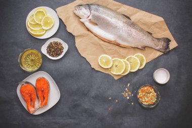 Çiğ balık ile baharat. Çiğ balık, limon dilimleri üzerinde beyaz tabak, limon, karabiber ve tuz somon karides ile kahverengi kraft kağıt üzerinde bir koyu gri masa yerleştirilir.