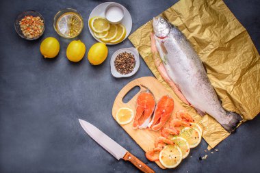 Çiğ balık ile baharat. RAW ağır Kraft kağıt üzerinde gri bir masa üstü limon böyle çiğ balık yağı tuz ile limon dilimleri baharat biber.