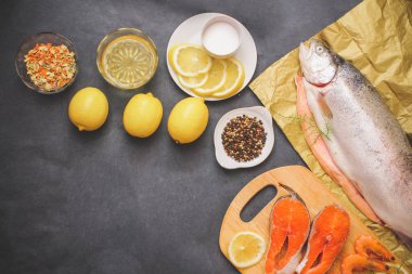 Çiğ balık ile baharat. RAW ağır Kraft kağıt üzerinde gri bir masa üstü limon böyle çiğ balık yağı tuz ile limon dilimleri baharat biber.