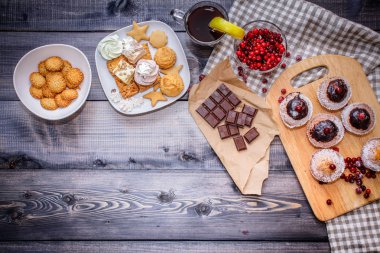 Mutlu yeni yıl kızılcık, tatlılar tatlı tabağı, kraft kağıt üzerinde kırık çikolata ve bir bardak koyu gri arka plan üzerinde keten peçeteye limonlu çay. Festival pasta kompozisyon.
