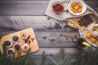Mutlu yeni yıl çam dalları gingerbread yıldız ile dekore edilmiş, tarçın sopa, kurutulmuş portakal dilimleri ve beze tepeler, parlak kızılcık, tatlılar tatlı tabağı, kraft kağıt üzerinde kırık çikolata ve bir bardak çay limon keten napki üzerinde