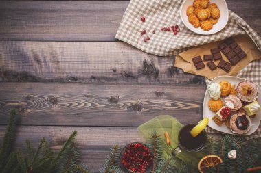 Mutlu yeni yıl çam dalları gingerbread yıldız ile dekore edilmiş, tarçın sopa, kurutulmuş portakal dilimleri ve beze tepeler, parlak kızılcık, tatlılar tatlı tabağı, kraft kağıt üzerinde kırık çikolata ve bir bardak çay limon keten napki üzerinde