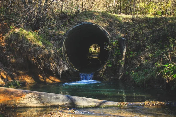 Le trou noir du tuyau, d'où coule un ruisseau bleu, coule — Photo