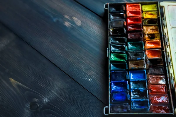 On a dark gray wooden tabletop, juicy watercolor paints, which t — Stock Photo, Image