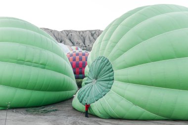 CAPPADOCIA, TURKEY - 09 MAY, 2018: high angle view of man working with hot air balloons in cappadocia, turkey clipart