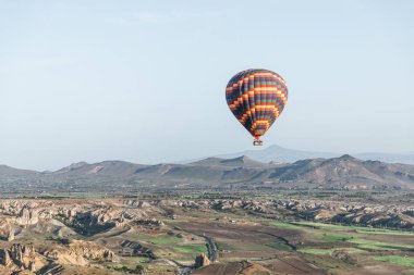 colorful hot air balloon flying above goreme national park, cappadocia, turkey clipart