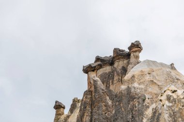 beautiful rock formations against cloudy sky in cappadocia, turkey clipart
