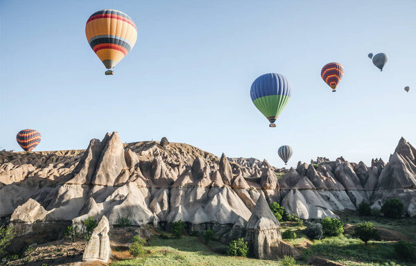 CAPPADOCIA, TURKEY - 09 MAY, 2018: colorful hot air balloons flying in sky above beautiful rock formations in cappadocia, turkey  