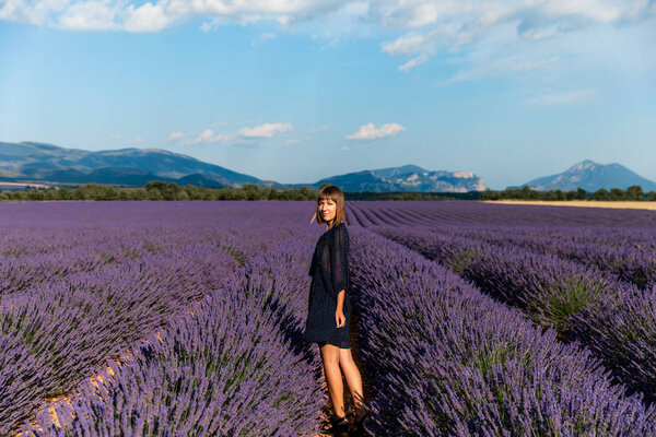 beautiful young woman standing on lavender field and looking at camera, provence, france