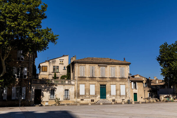 empty street with old traditional houses and green trees at sunny day, provence, france