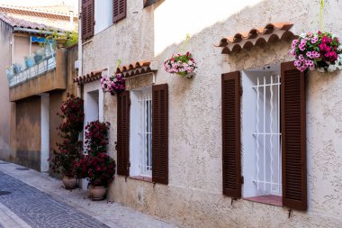 cozy narrow street with traditional houses, flower pots and shutters in provence, france clipart