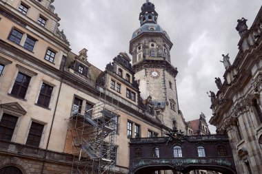Low angle view of old dresden cathedral with clock, statues on building roof in Dresden, Germany