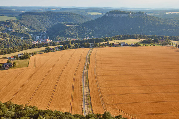 aerial view of road between beautiful orange fields with harvest in Bad Schandau, Germany