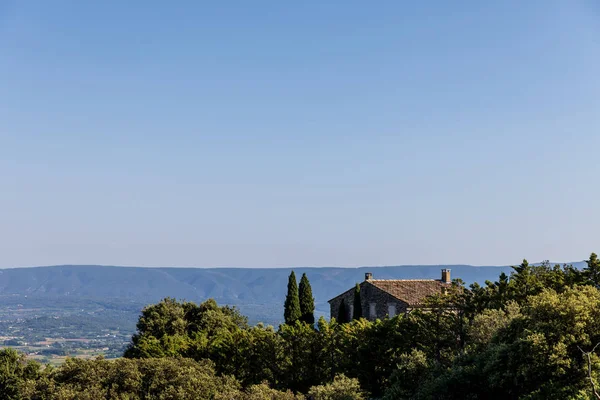 Paisaje tranquilo con granja solitaria, árboles verdes y montañas lejanas en la granja provence - foto de stock