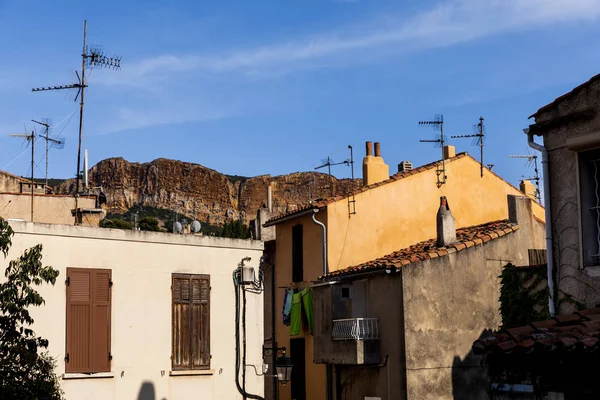 Casas tradicionales en la calle estrecha y montañas rocosas distantes en provence, Francia - foto de stock