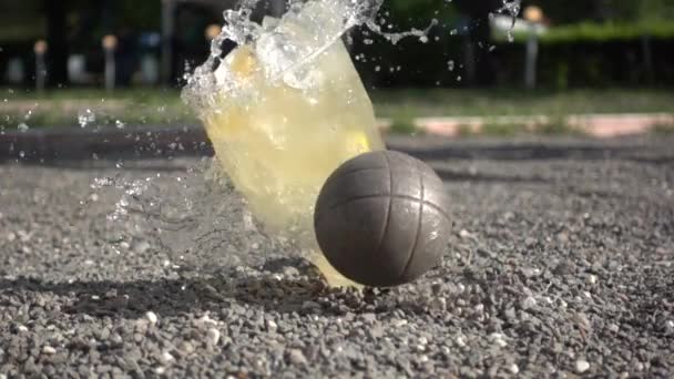 Uma bola petanque derruba um copo com uma bebida . — Vídeo de Stock