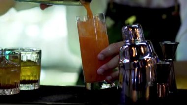 Barmen barda karışık bir içki koyuyor. İçki bardaklarını yakın çekim..