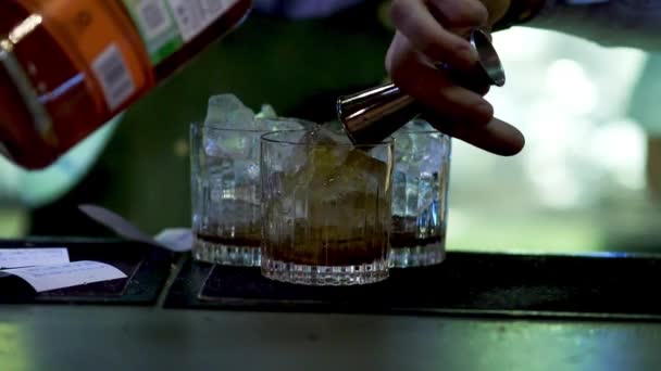 Barman nalije do baru míchaný nápoj. Skleničky na pití detailní záběr. — Stock video