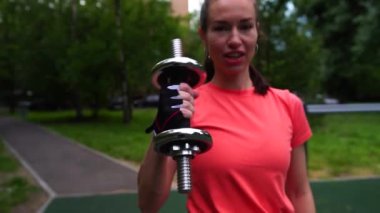 Kız parkta dambılla antrenman yapıyor. Yavaşlama Hareketi.