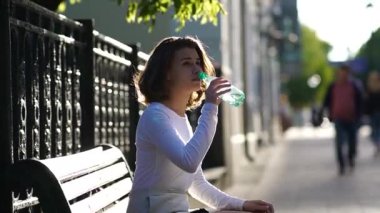 Güzel kız kentteki bankta dinleniyor.