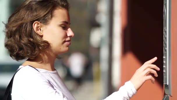 Девушка нажимает кнопку домофона в доме — стоковое видео