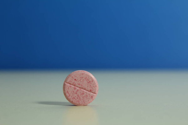 Capsule pills medical, white and pink, on a blue background.