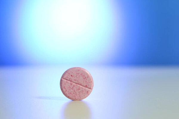 Capsule pills medical, white and pink, on a blue background.
