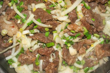 Sulu biftek, kavrulmuş tecrübeli, Yeşiller ve soğan ile kısık ateşte.
