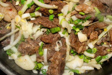 Sulu biftek, kavrulmuş tecrübeli, Yeşiller ve soğan ile kısık ateşte.