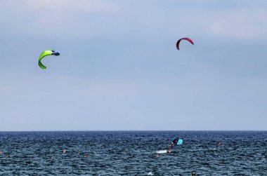 Albenga, Liguria, İtalya. Temmuz 2018. Kitesurfing Albenga deniz üzerinde mavi gökyüzü parlak renkli yelken canlandırmak. Su yüzeyinde yelken sallamaları panoları yollar.