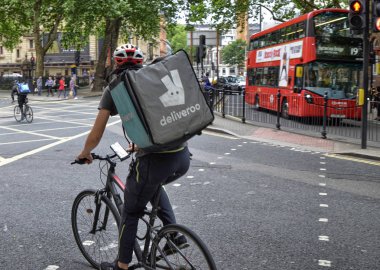 Londra, İngiltere, Haziran 2018. Deliveroo, size en yakın restoranlarından ev teslim yönetir bir şirket bir işçi. Binici juggles teslimatı yapmak için kentsel trafik aracılığıyla.