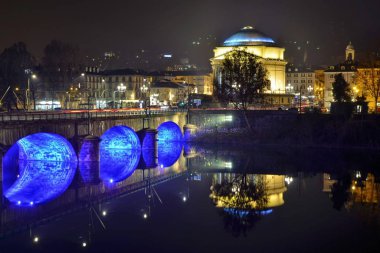 Turin, Piedmont, İtalya. Aralık 2018. Piazza Vittorio tarafında Po Nehri üzerinden fotoğraflandı Tanrı büyük anne Kilisesi. Yılbaşı partileri için aydınlatma artistik bir dokunuş verir.