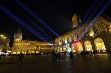 Bologna Emilia Romagna, İtalya. Aralık 2018. Piazza Maggiore için yeni yıl kutlamaları hazırlıkları içinde. Renkli ışıklar karanlık gece gökyüzüne karık. İnsanlar yürüyüş.