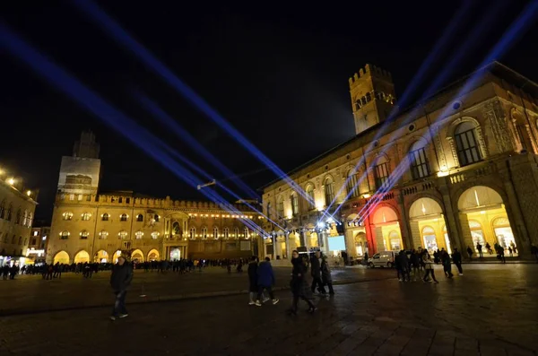 Bologna Emilia Romagna, İtalya. Aralık 2018. Piazza Maggiore için yeni yıl kutlamaları hazırlıkları içinde. Renkli ışıklar karanlık gece gökyüzüne karık. İnsanlar yürüyüş.