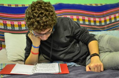 Kıvırcık kumral ve gözlük bir beyaz çocuk, okuyor