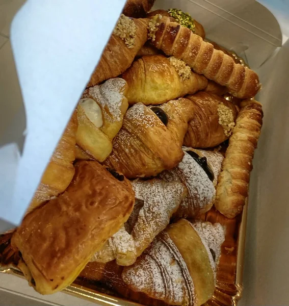 A pastry box filled with cannoli, croissants and croissants